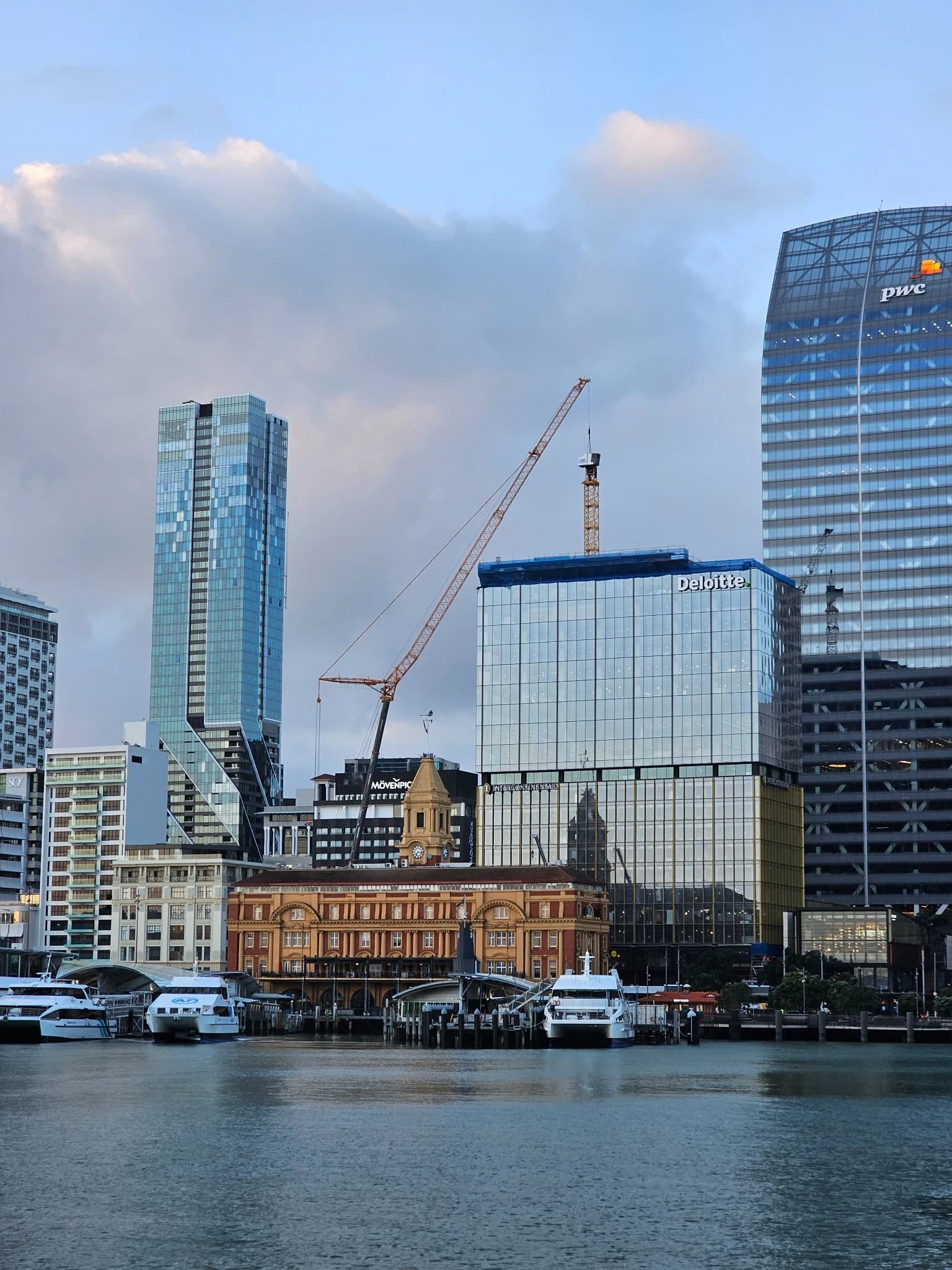 Auckland's waterfront with the Ferry Building and the harbour, a tower crane behind the city towers.